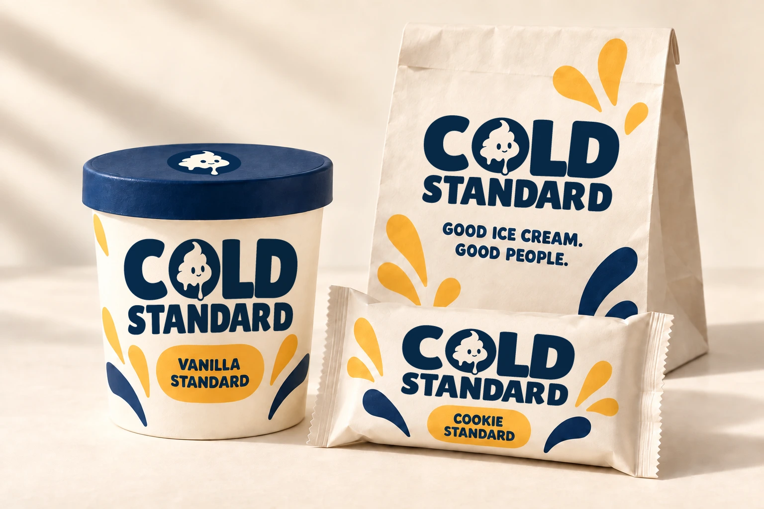 Concept visualization of the Cold Standard packaging family: a cream Vanilla Standard pint with a navy lid, a takeaway bag reading Good ice cream. Good people., and a Cookie Standard sandwich wrapper, each with the navy Cold Standard logo.