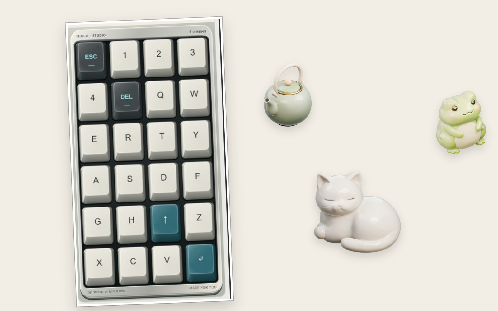 Little Desk: a mechanical keyboard app on a phone-sized board of ivory and teal keycaps, with small ceramic keepsakes, a teapot, a cat and a frog, resting on the cream desk beside it.